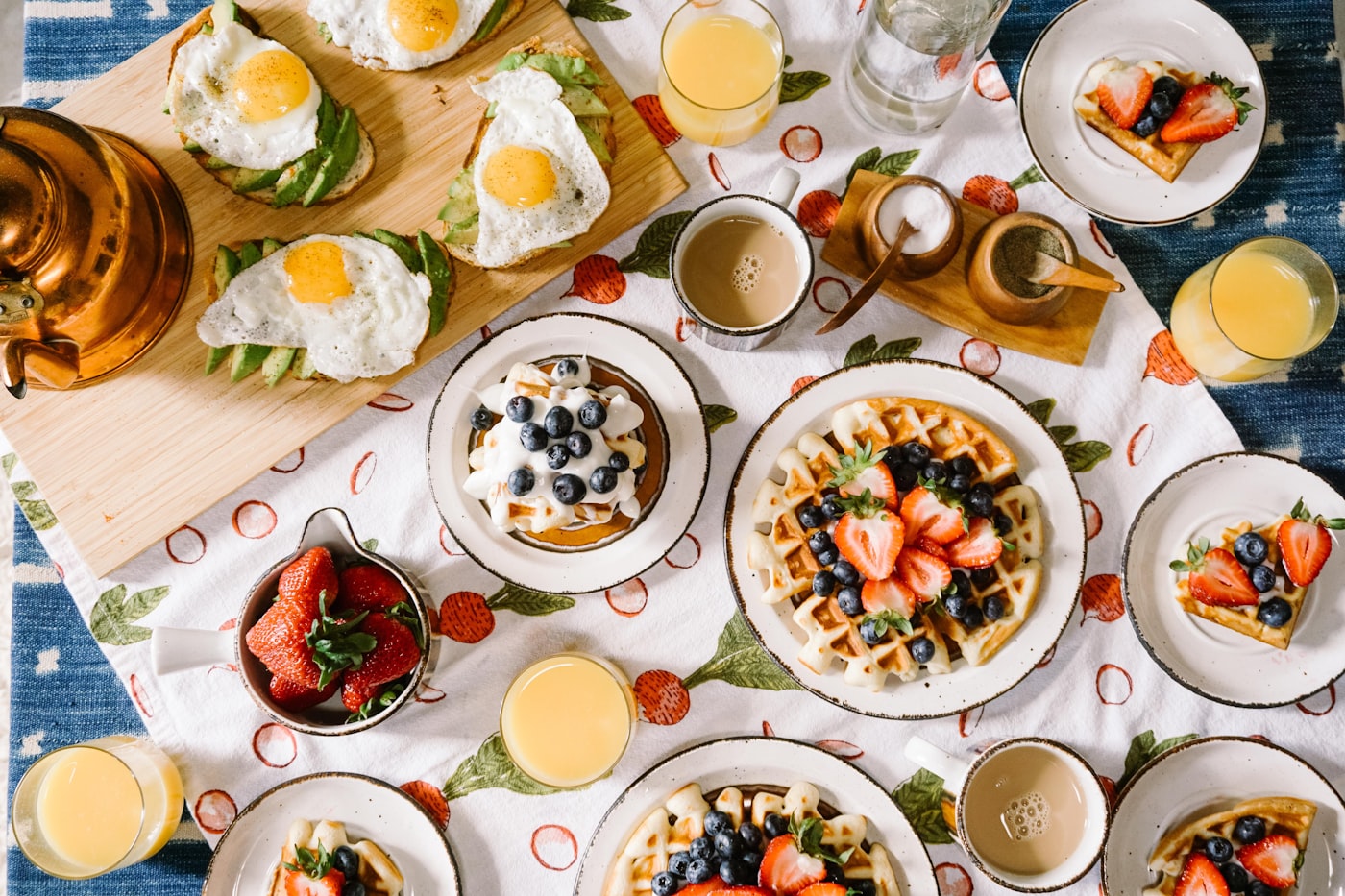 Mesa de brunch con gofres, huevos, fruta fresca, zumo de naranja y café
